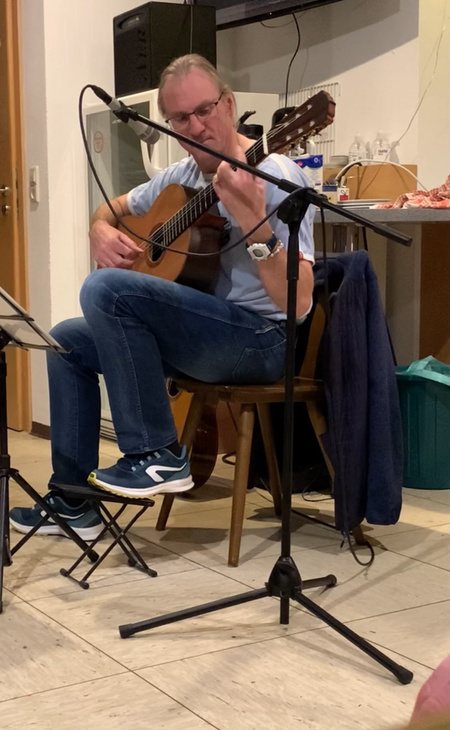Stefan „Leff“ Mertenbaur sitzt mit Gitarre vor einem Mikrofon