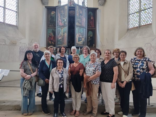 Gruppe der Damengymnastik in einer Kirche vor einem Flügelaltar