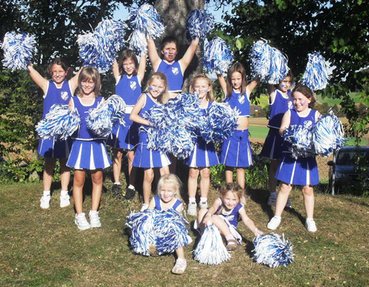 Tänzerinnen in blau-weißen Cheerleader-Outfits mit Pompons im Freien