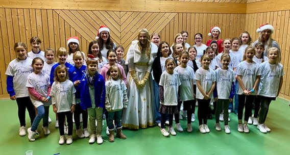 Große Gruppe der Dancers in weißen Shirts mit Weihnachtsmützen in der Turnhalle