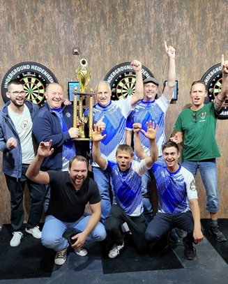 Jubelnde Walter-Frosch-Darters mit einem großen Pokal vor Dartscheiben