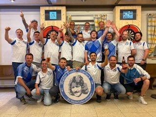 Gruppenfoto der Dartspieler mit einer Scheibe mit dem Porträt von Walter Frosch