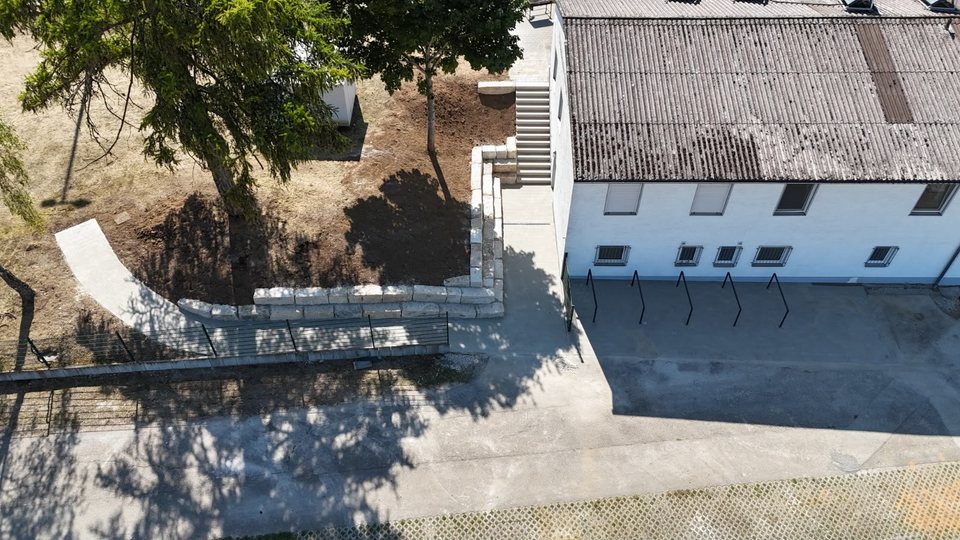 Luftaufnahme der neuen Natursteinmauer und Treppe am Hang neben dem Sportheim