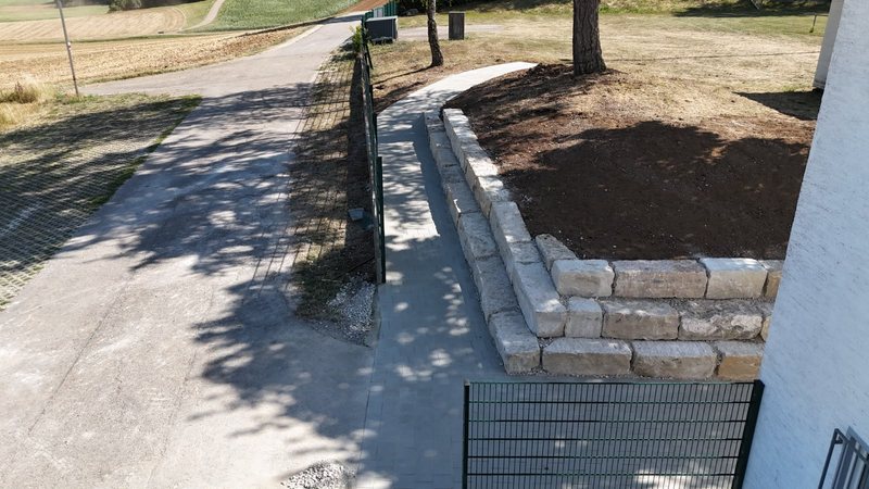 Neu gepflasterter Weg entlang einer Natursteinmauer
