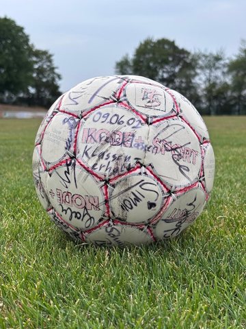 Signierter Fußball mit der Aufschrift Klassenerhalt und dem Datum 09.06.02 auf dem Rasen