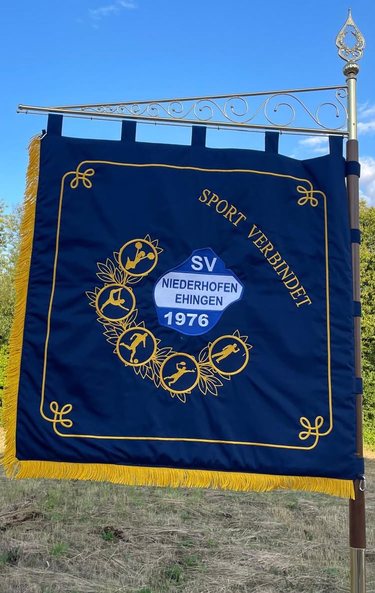 Blaue Vereinsfahne mit dem Wappen, einem Kranz aus Sportsymbolen und der Inschrift Sport verbindet