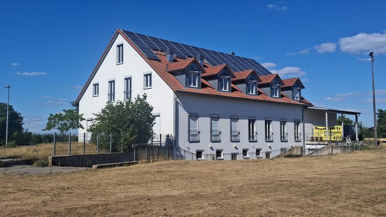 Weißes Gemeindevereinszentrum mit Gauben und Solaranlage auf dem Dach