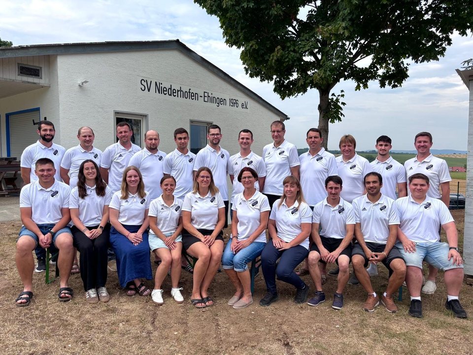 Gruppenfoto der Vorstandschaft in weißen Poloshirts vor dem Sportheim mit der Aufschrift SV Niederhofen-Ehingen 1976 e.V.